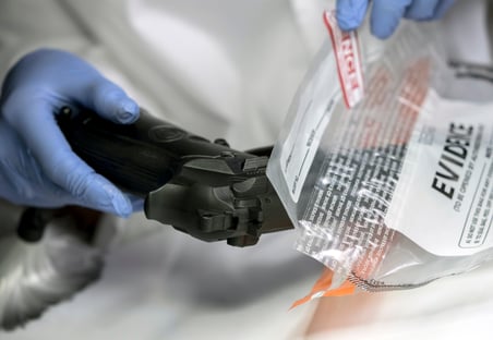 scientific-police-officer-examining-traces-of-a-gun